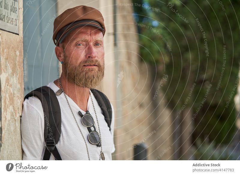 Hipster male traveler with backpack hipster man trendy style beard backpacker adult hiker portrait cap accessory modern confident serious tourism individuality