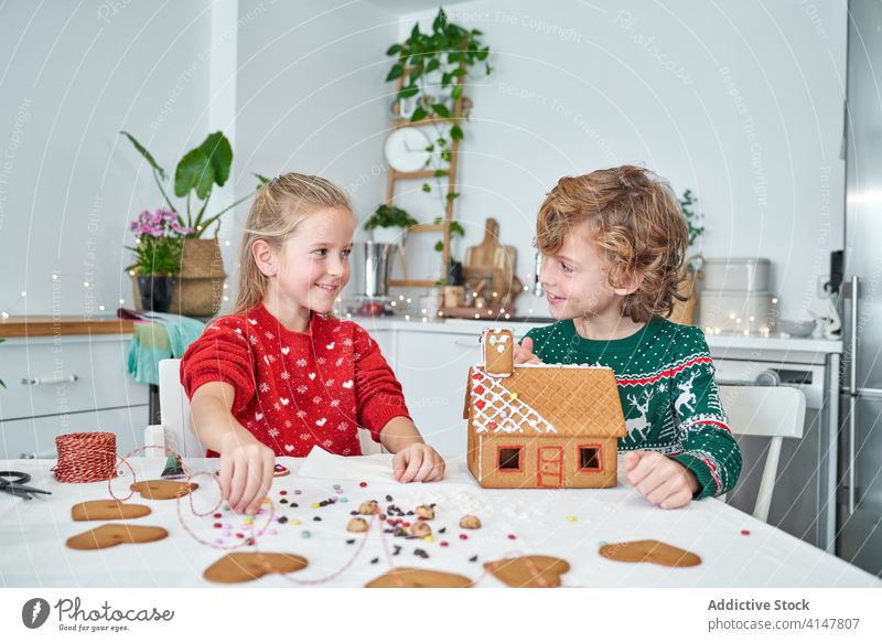 Happy kids making gingerbread houses christmas happy prepare make together children cheerful home kitchen sibling little smile winter festive tradition joy