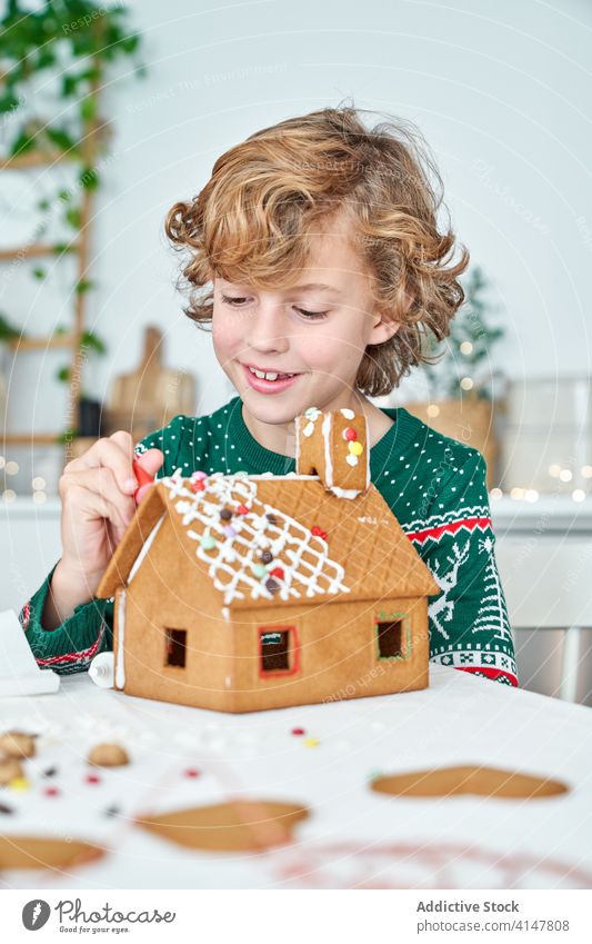 Little boy decorating gingerbread houses kid christmas icing prepare make decorate home kitchen little child winter festive holiday homemade occasion male