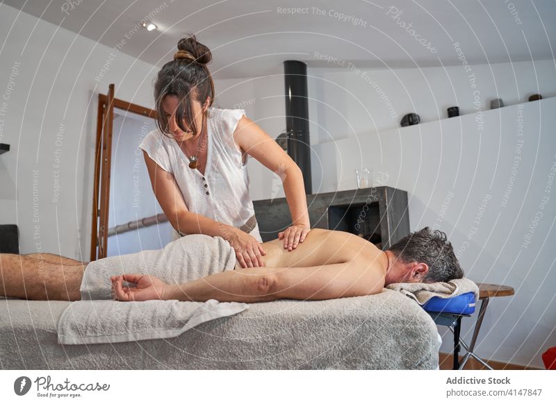 Masseuse massaging back of relaxed client massage salon woman masseur knead body care healthy therapist female table therapy patient tranquil spa health care
