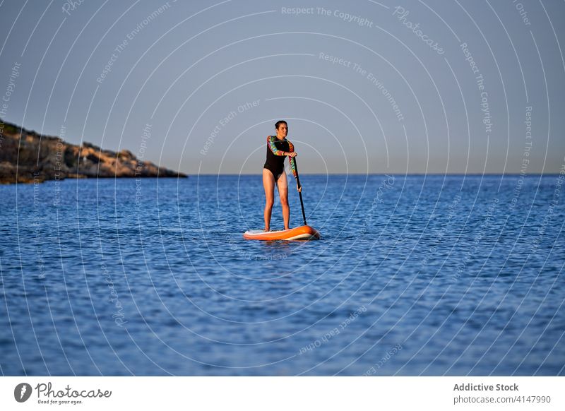 Fit woman floating on paddleboard in sea surf surfer row practice fit slim swimsuit female surfing activity surfboard sport vacation ocean summer sporty active