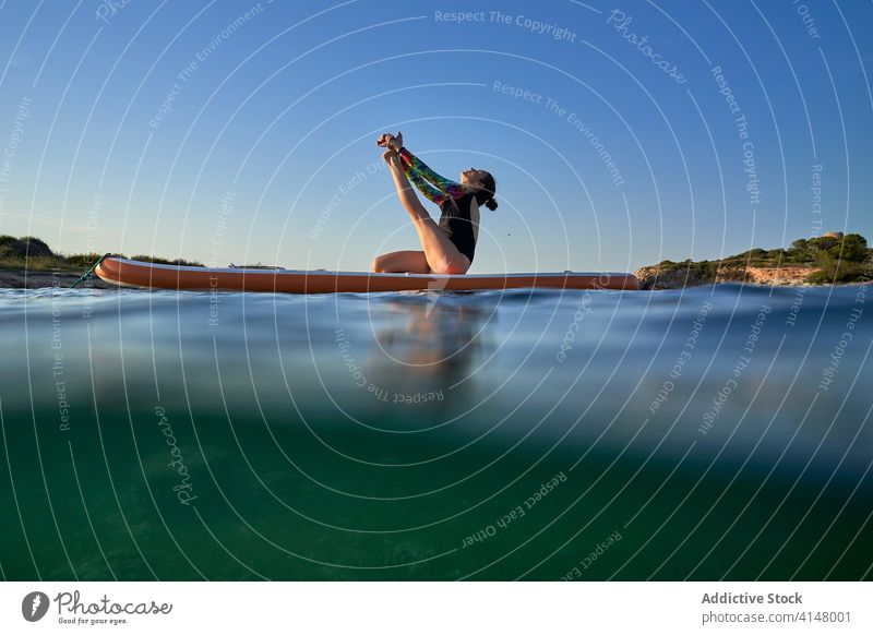 Flexible woman doing yoga on paddleboard sunset pose surfer balance sea female water healthy nature harmony relax tranquil serene sky calm ocean peaceful lady