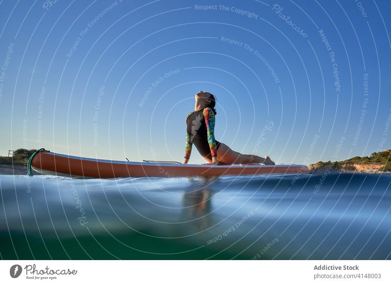 Flexible woman doing yoga on paddleboard sunset pose surfer balance sea female water healthy nature harmony relax tranquil serene sky calm ocean peaceful lady