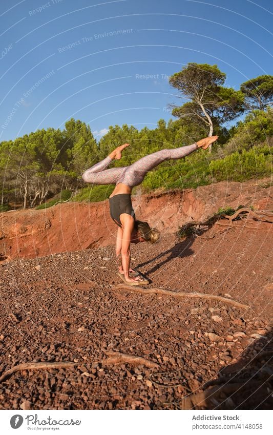 Blonde woman practicing a variation of handstand yoga pose in the middle of the forest natural tights inverse fitness sport strength health girl healthy athlete