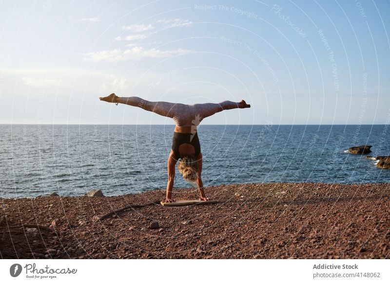 Woman doing the handstand yoga position in front of the sea light vertical triangle beach isolated fitness sport strength health woman girl healthy athlete