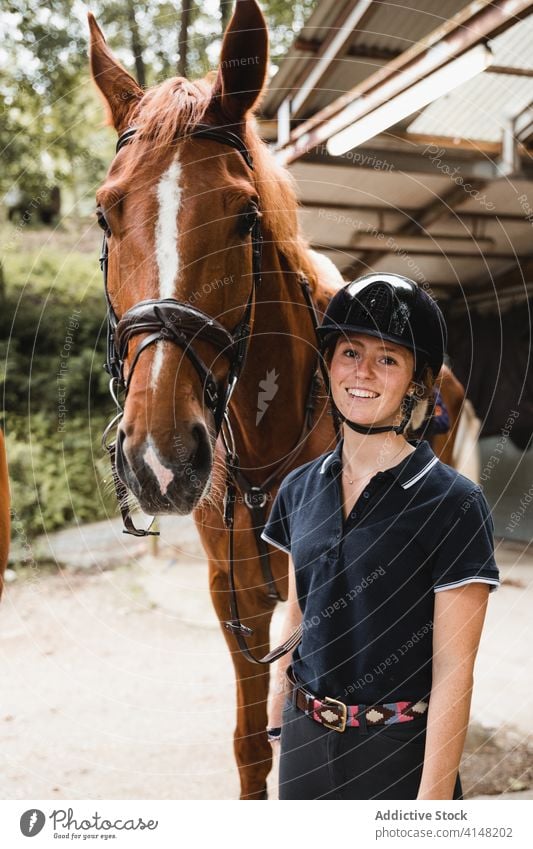 Content jockey with horse on ranch equestrian bridle woman prepare animal reins smile together female rider tool equipment equine young concentrate serious