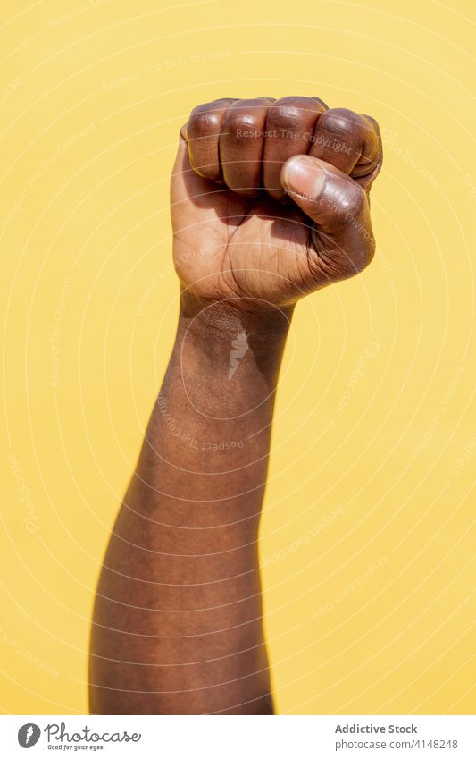 vertical photo of a raised fist of a black man protest person right fight power hand freedom strength human revolution strong arm up anger punch rebellion