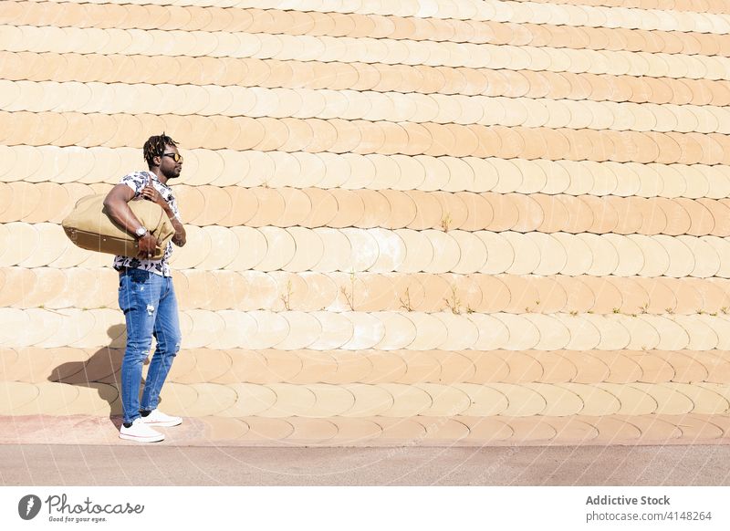 young black man with sunglasses and a travel bag person big male large carry carrying standing traveler tourist handsome guy journey horizontal copy space