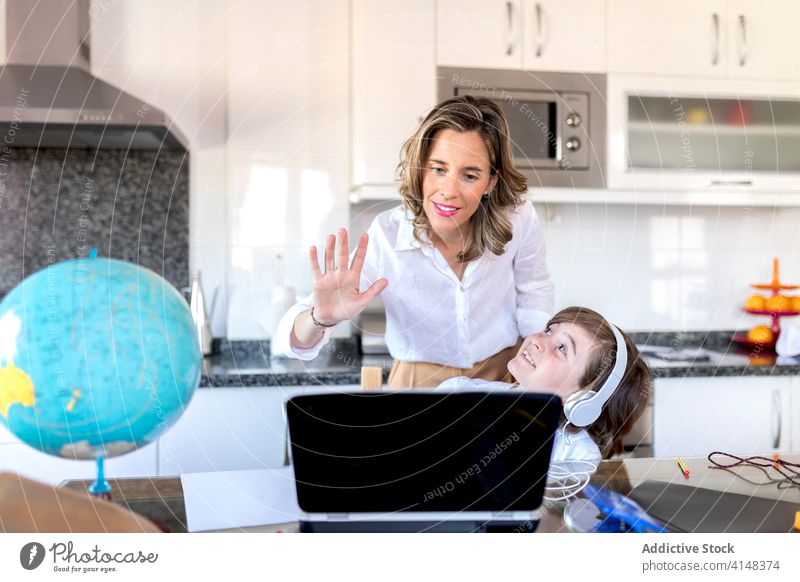 Mother with son saying hello during video call on laptop mother greeting embrace communicate childhood using device gadget watching netbook internet online
