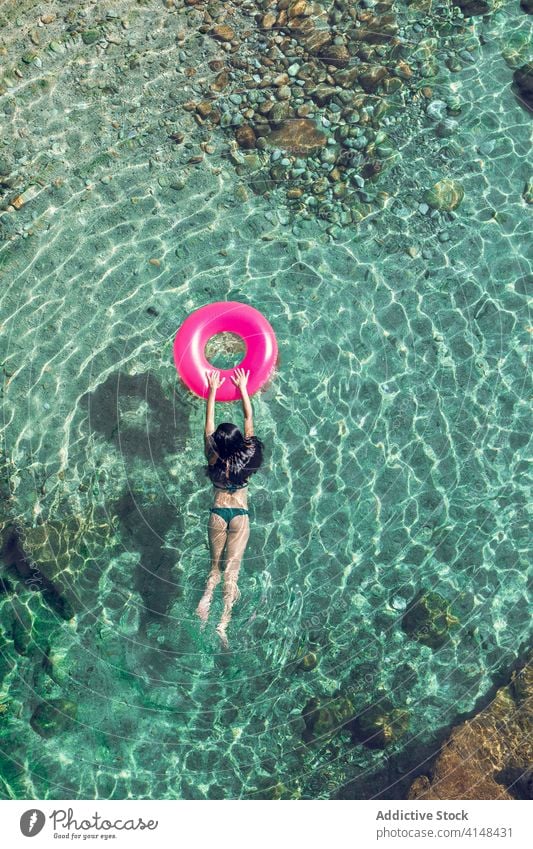 Woman swimming in water with ring woman vacation resort summer swimwear sunglasses transparent female inflatable tube sunny daytime relax recreation rest