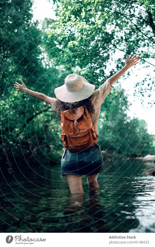 Content woman in river in forest enjoy vacation summer tourism cheerful holiday water relax travel happy hat journey adventure carefree nature trip freedom lady