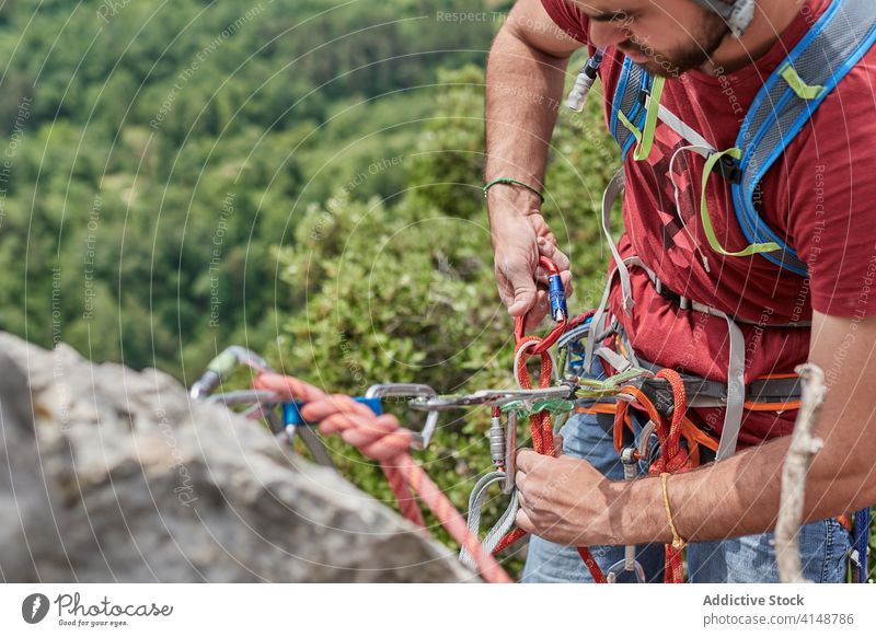 Male mountaineer hanging on rope alpinist man carabine adjust harness safety rock male adventure climb protect helmet nature equipment extreme activity strong