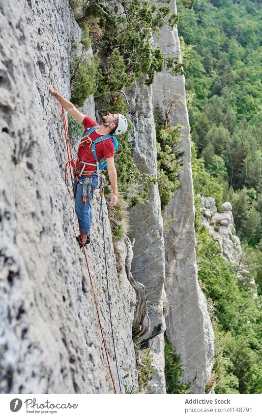 Male alpinist on rope on rock climb mountaineer man extreme risk safety alpinism male adventure equipment steep summer vacation nature challenge explore journey