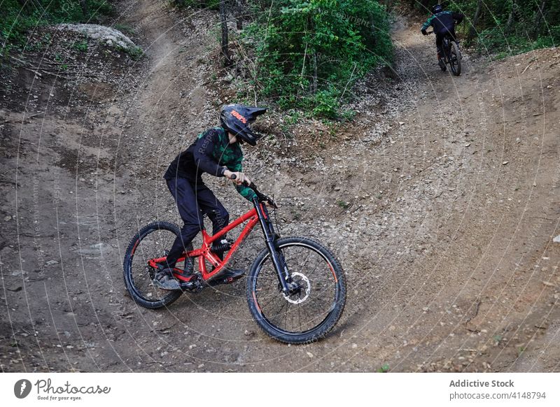 Cyclist riding bicycle in forest downhill trick man extreme stunt ride cyclist risk helmet enduro perform professional woods woodland nature protect activity