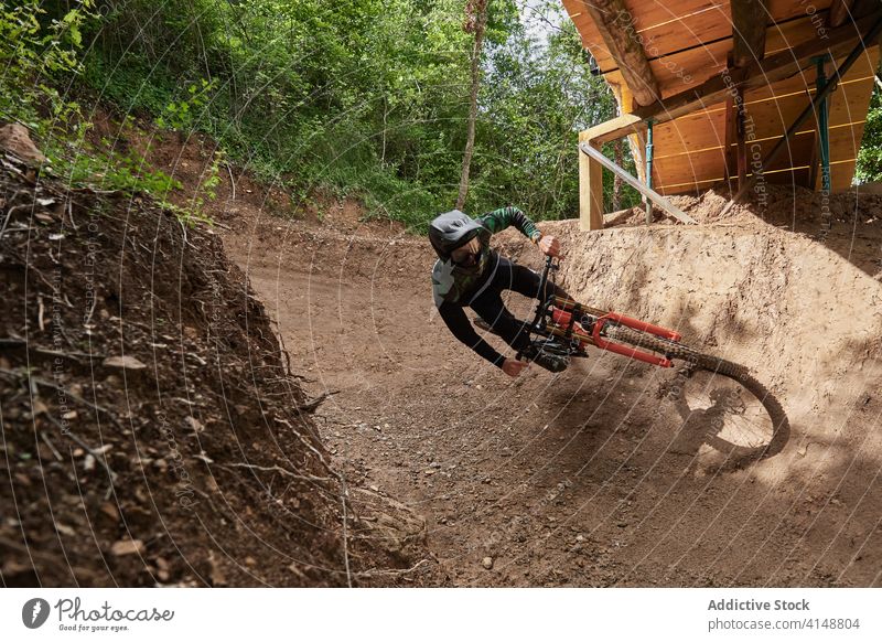 Cyclist riding bicycle in forest downhill trick man extreme stunt ride cyclist risk male helmet enduro perform professional woods woodland nature protect