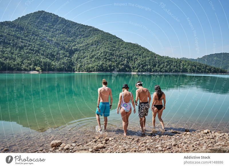 Friends relaxing on lake in mountains friend vacation together water pond highland company summer sunny calm swimwear nature environment landscape freedom