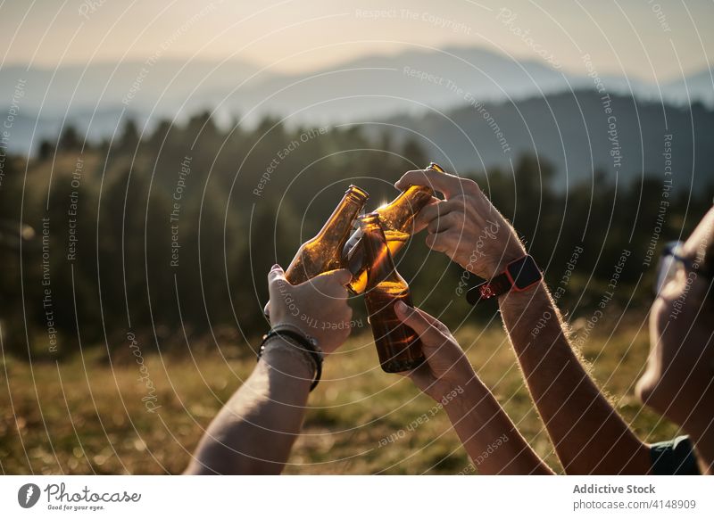 Friends clinking bottles in mountains enjoy weekend friend group relax alcohol summer highland company together beverage beer sunset drink rest cheers cheerful