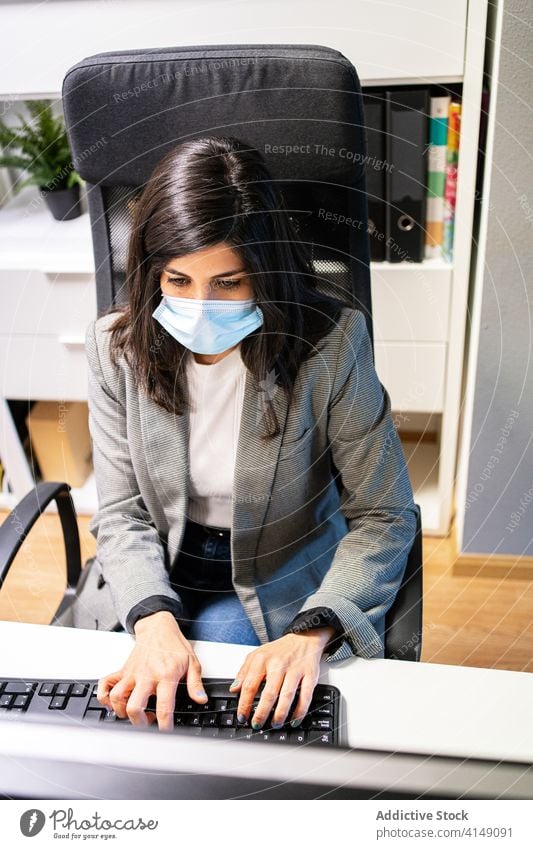 Young woman in medical mask working on computer in workplace office workspace using busy business protect coronavirus pandemic covid19 covid 19 new normal