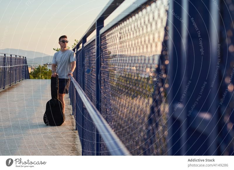 Serious man with guitar in city musician guitarist bridge calm serious talent player male case confident handsome relax modern urban sound instrument stand
