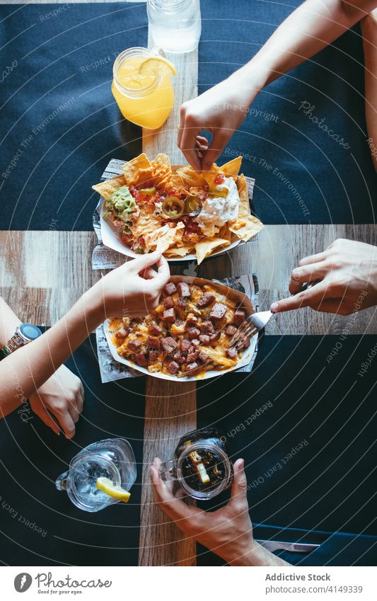 Friends eating delicious snacks in cafe food friend together meeting meal bacon fries nachos lunch fried gather yummy group avocado people hand tasty restaurant