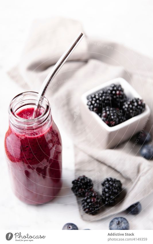 Vertical close up shot of a glass bottle with berry smoothie and a metal straw inside. Berry smoothie Bottle Close up Color Drink Food and drink Fruits