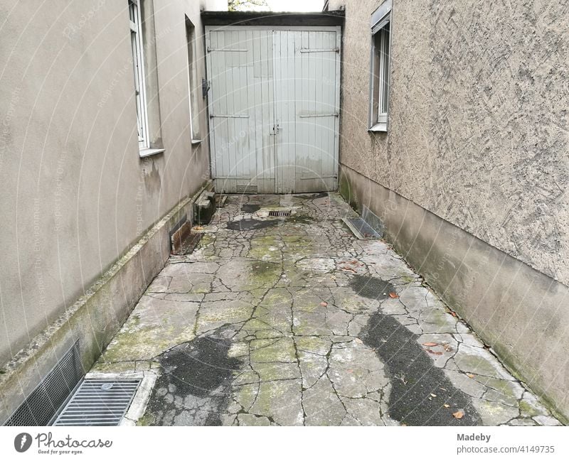 Narrow courtyard entrance with cracked stone slabs and old wooden door of a garage in Lemgo near Detmold in East Westphalia-Lippe Courtyard Courtyard entrance