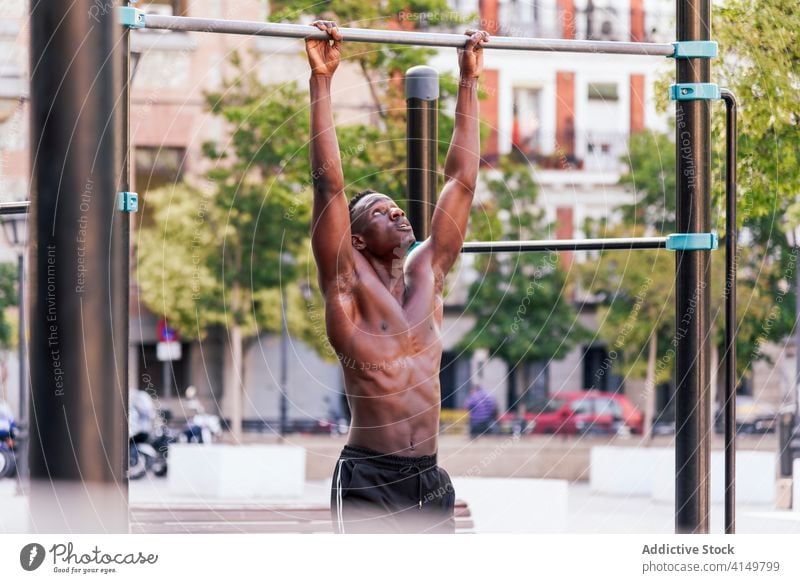 Muscular black sportsman doing pull ups training strong exercise athlete effort stamina naked torso workout male ethnic african american intense fitness
