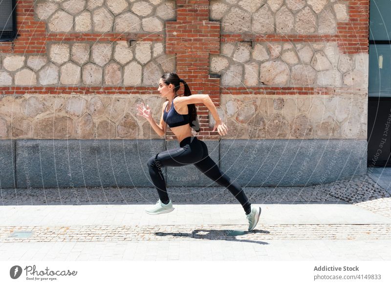 Woman running fast along street in city runner woman training sunny fit sportswoman speed female pavement exercise athlete sportswear workout vitality fitness