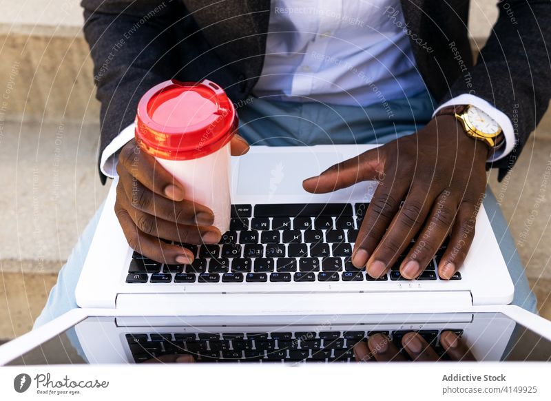 Anonymous black man entrepreneur with laptop and coffee on street businessman drink using urban confident formal modern young african american ethnic cup