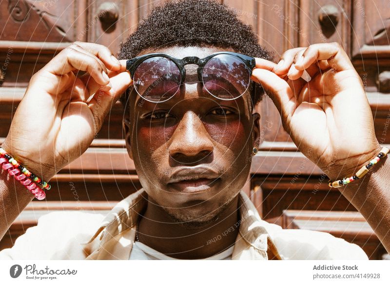 Calm black man in sunglasses in city style afro trendy hairstyle urban hipster emotionless male ethnic african american barcelona spain fashion modern cool