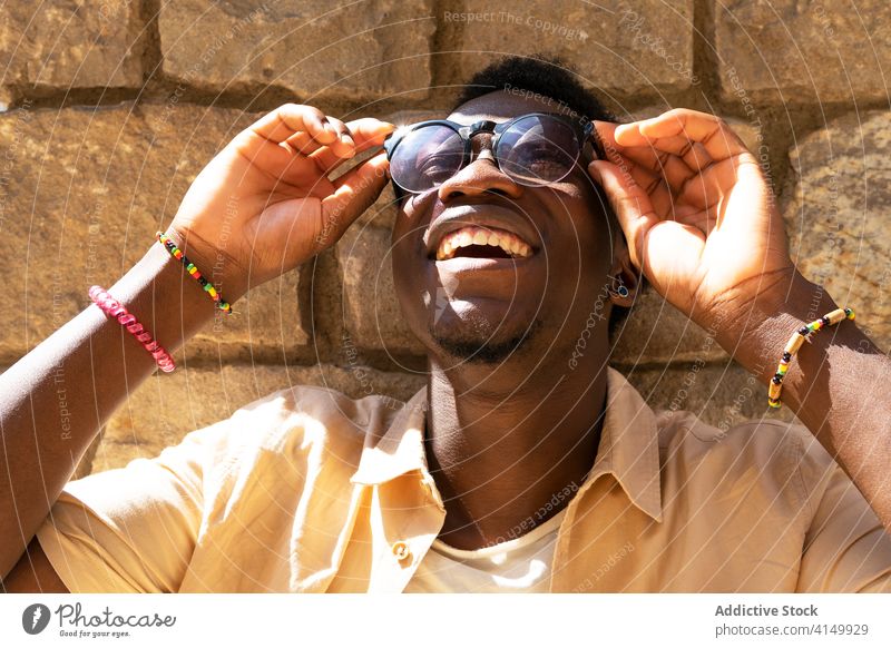 Delighted ethnic man in sunglasses style cheerful city trendy delight summer sunny carefree male black african american barcelona spain outfit lean street