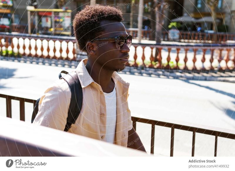 Black man in city in summer stroll walk sunlight sunglasses relax calm weekend male ethnic black african american barcelona spain street style daytime pavement