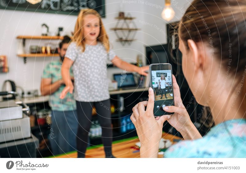 Mother recording her daughter dancing with the mobile while working in a coffee shop mother video social media cell phone happy family picture photo father