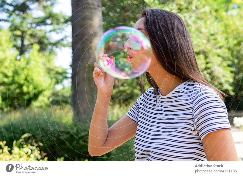 Young woman blowing bubbles in park soap bubble childish carefree summer entertain enjoy female playful garden green relax weekend nature fun young rest lady