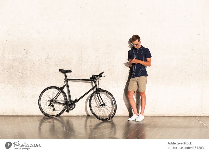 Man leaning on wall on the smartphone bicycle bike blond business caucasian browsing mobile phone communication copy space cycling cyclist entrepreneur