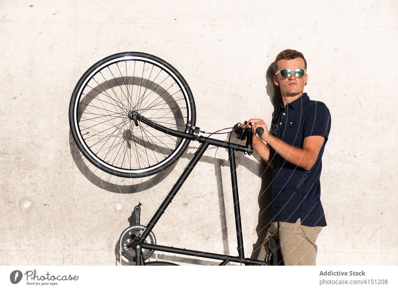 Man carrying his bicycle on concrete wall adult bike blond casual caucasian cycling cyclist lifestyle lean male man hold millennial mobility modern people