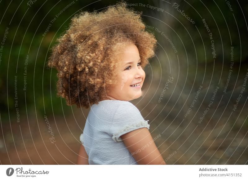 Happy curly haired girl in summer field happy cheerful kid smile portrait mixed race adorable hairstyle cute joy female ethnic afro child childhood charming