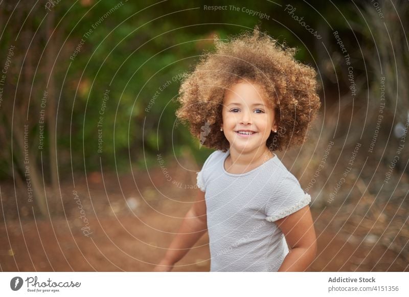 Happy curly haired girl in summer field happy cheerful kid smile portrait mixed race adorable hairstyle cute joy female ethnic afro child childhood charming