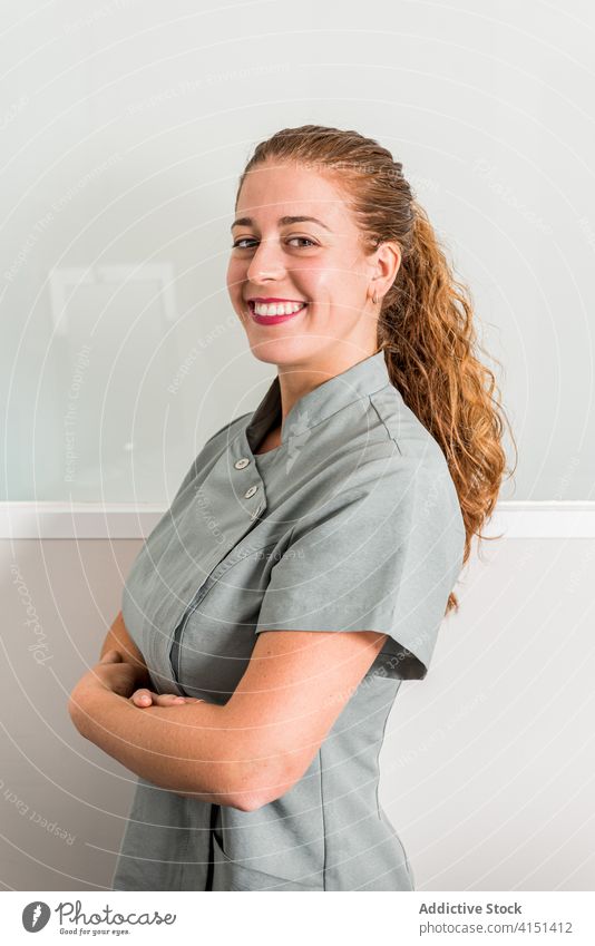 Happy young female salon worker looking at camera woman clinic uniform happy smile friendly staff portrait confident positive specialist cheerful job service