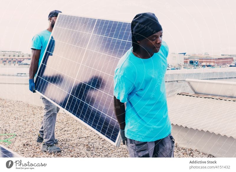 Ethnic men with solar panel on construction site industrial alternative work sustainable renewal ethnic black african american together sunny area modern walk