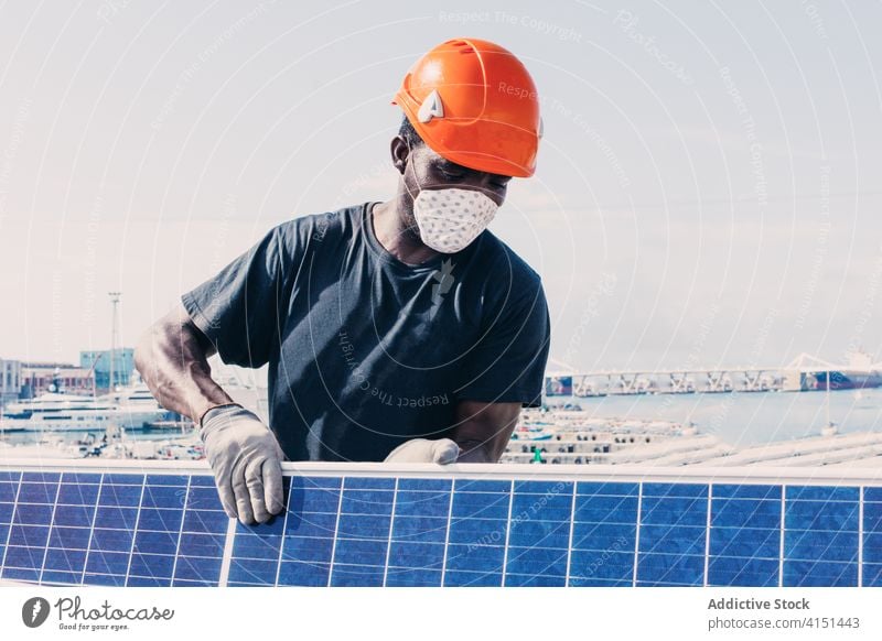 Male worker in mask with solar panel install battery man engineer alternative sustainable power male ethnic black african american development energy resource