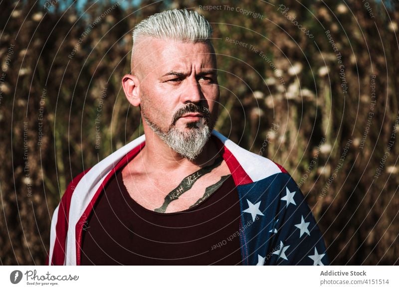 Brutal adult man with American flag brutal serious beard american confident hard portrait strong male tattoo gray hair middle age nature usa patriot independent