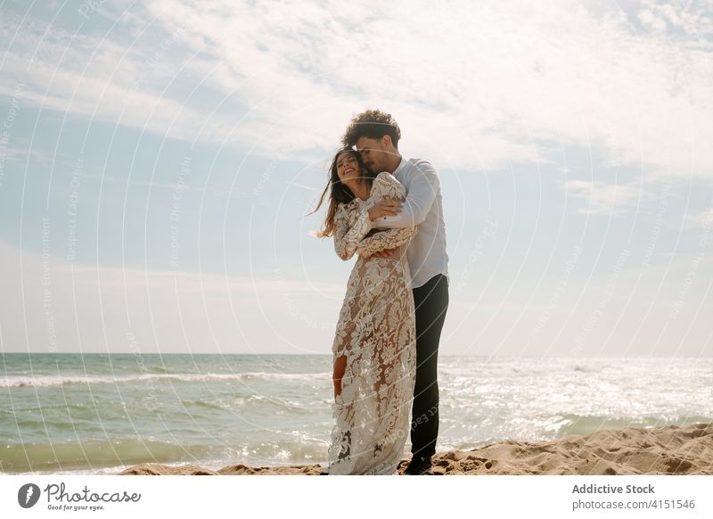 Happy newlywed couple standing against waving sea beach romantic happy cheerful together embrace relationship love nature sand gentle seaside harmony amorous