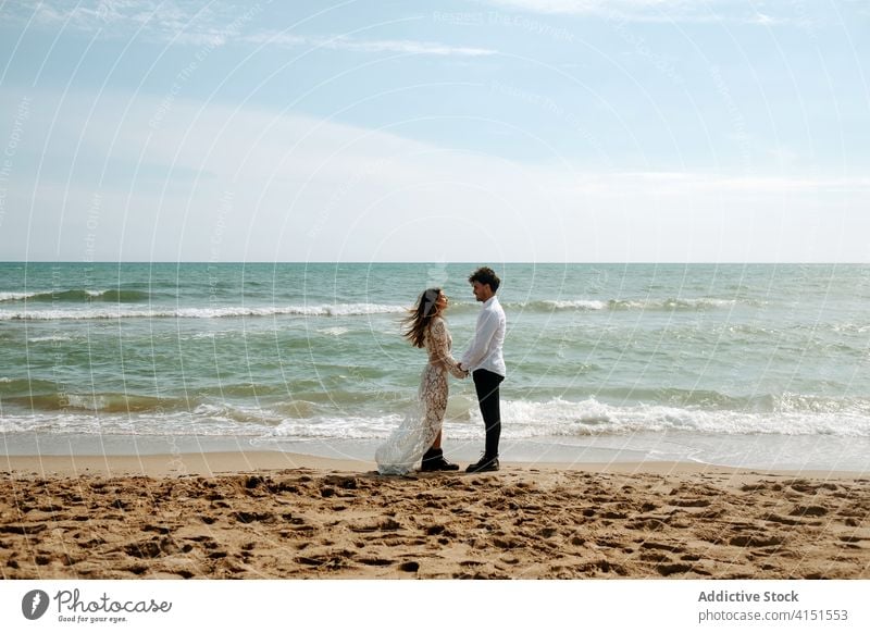 Loving couple standing near sea waves romantic newlywed beach together relationship love gentle tender enjoy seaside nature sand harmony looking at each other