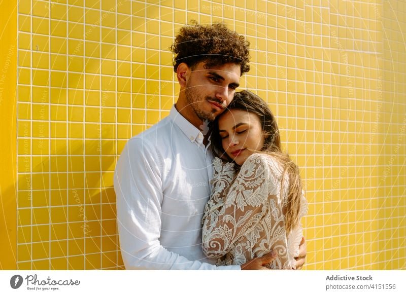 Stylish romantic couple hugging near wall love embrace tender care newlywed together relationship gentle harmony amorous fondness married amour style young