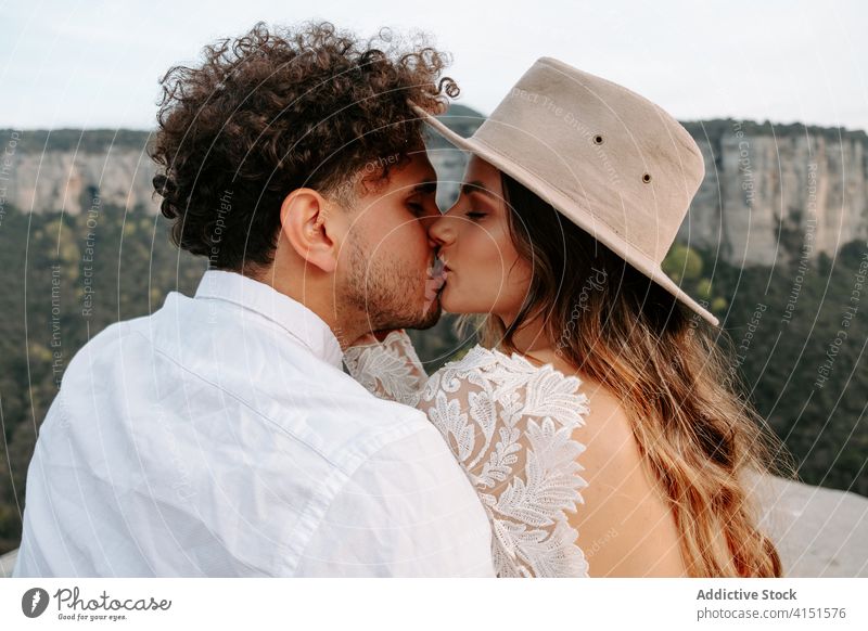 Tender newlywed couple kissing in mountains romantic love young rock happy nature together relationship wedding boho bride groom spain morro de labella