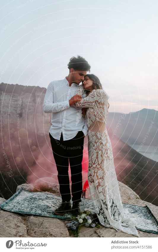 Newlywed couple enjoying romantic moments in mountains newlywed love rock gentle tranquil cliff nature smoke tender sensual celebrate young eyes closed edge