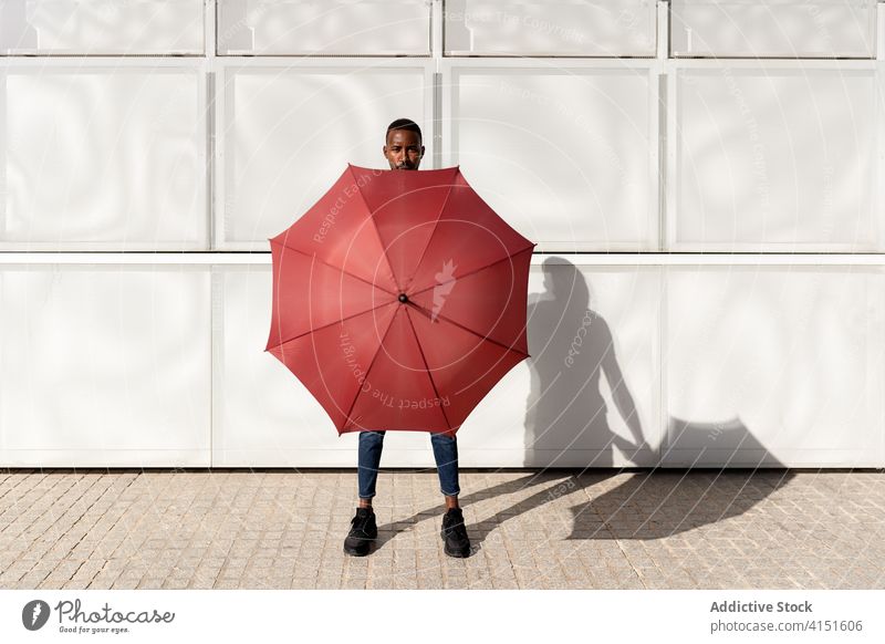 African American man with umbrella in street cover hide summer sunny city urban pavement male ethnic black african american sidewalk body town trendy weather