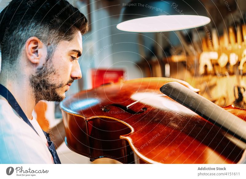 Artisan examining musical instrument in workshop luthier repair artisan make check restore man craft tool equipment violin cello guitar skill master concentrate