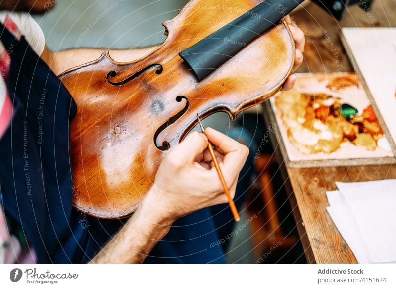 Anonymous luthier restoring old violin in workshop restore paint instrument repair artisan make man craft tool renew lacquer equipment skill master male maker